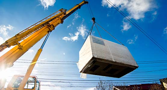 Yellow crane lifting a large white cargo against blue sky.